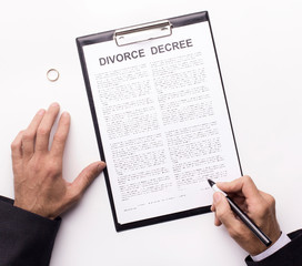 Husband signing divorce decree on white, wedding ring