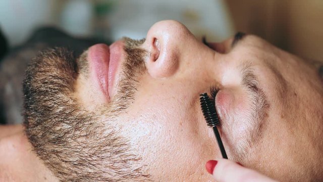 The face of handsome man after the procedure for laminating eyelashes in a beauty salon. Modern eyelash healing. Professional procedure for lamination and Botox eyelashes for men
