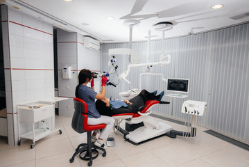 The dentist looks through a microscope and performs surgery on the patient