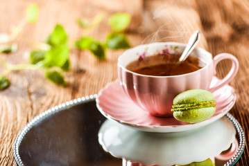 Sweet cake macarons and green tea. Colorful macarons with tea and mint on wooden table.