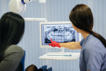 Naklejka premium The dentist shows a picture of the patient's teeth and tells the necessary treatment. Dentistry, health.