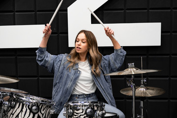 Creativity and music. Young beautiful girl plays the drums. Recording Studio. Musical equipment.