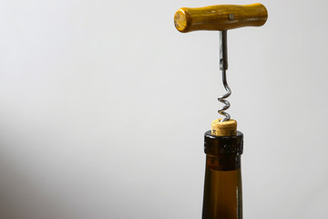 Metal corkscrew with a wooden handle screwed into a bottle stopper with red dry wine. Healthy use...
