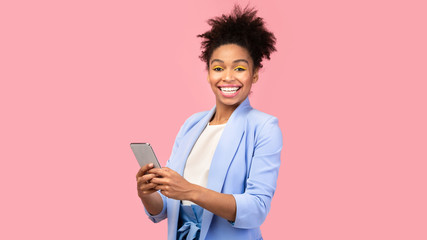 Smiling afro girl using cellphone looking at camera