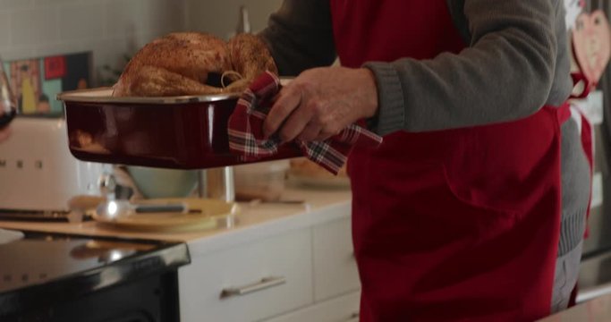 Father and daughter removing Thanksgiving turkey from oven