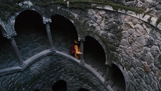girl in yellow jacket going down at mystery Quinta da Regaleira park well
