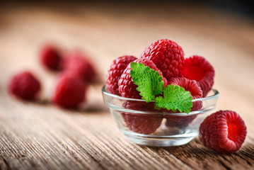 Fresh raspberry in glass bowl, on wooden board. Ripe raspberries freshly collected.