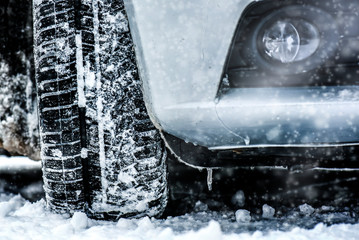 Winter tire. Car on snowy road. Tires on snow highway close up.