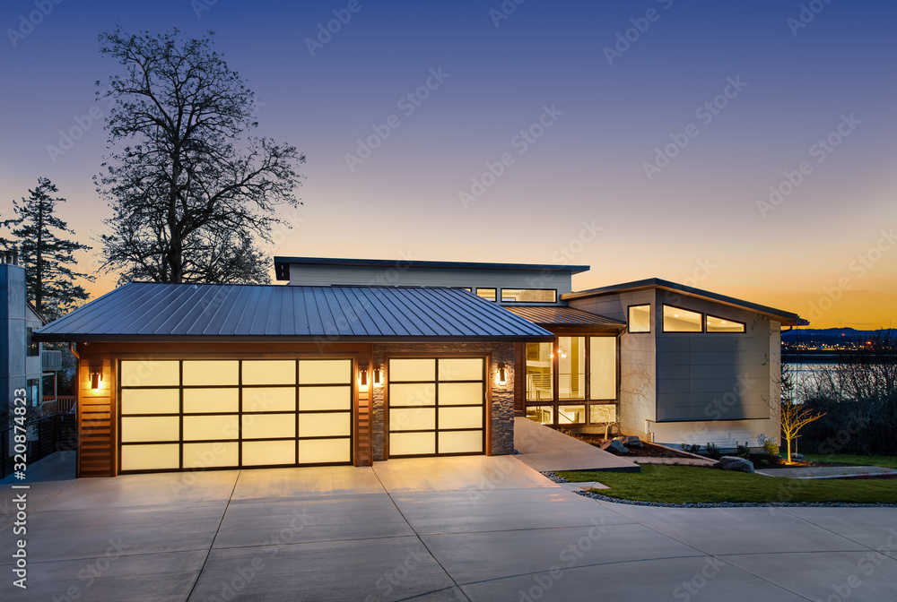 Wall mural beautiful modern style luxury home exterior at sunset with glowing interior lights. features three c