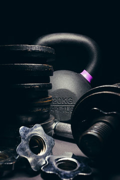 Black kettlebell  with purple marking with free weights and plates in front of it
