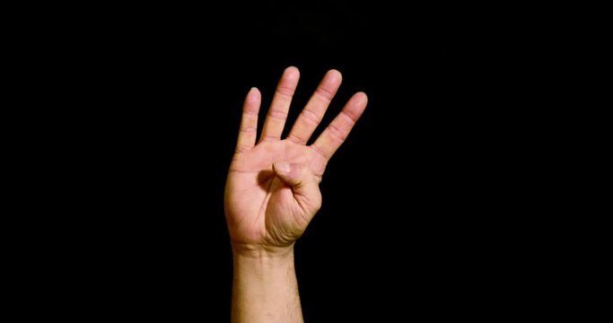 Male hand showing the number four on black background
