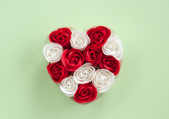 Red and white roses heart-shaped on a green background. Festive background for Valentine's day
