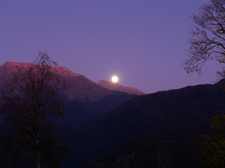 High beautiful mountains in the evening against the backdrop of a moon's fostoride which is out of focus