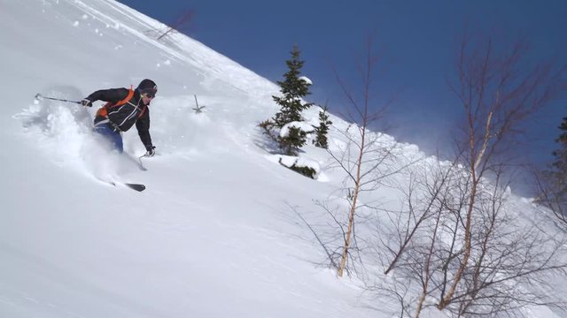 Skier Riding down in powder snow backcountry descent, extreme skiing on remote backcountry in Russia Siberia