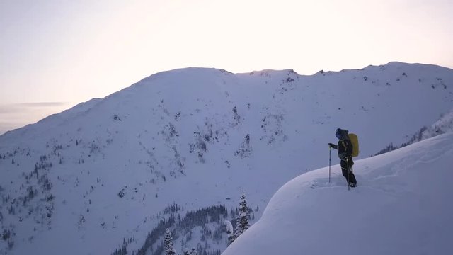 Skier Standing on the top edge of Mountain during sunrise, skitouring in the mountains