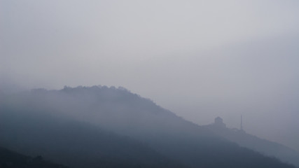 Medieval castle on the side of the mountain in fog