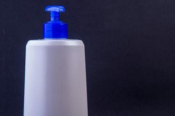empty cream bottle with dispenser on black