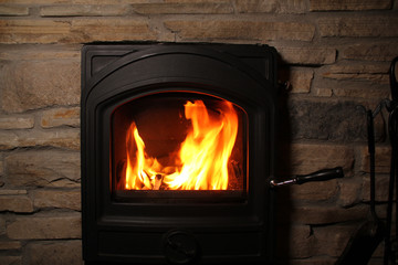 beautiful red flame of fire from burning firewood in an iron black fireplace, the concept of a cozy house