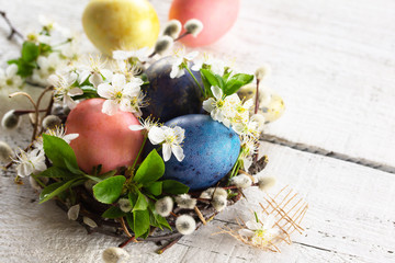 Colored Easter eggs and spring flowers on a white wooden background. Copy space.