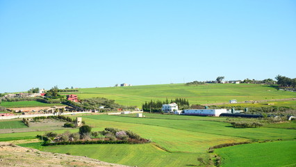 Naklejka premium Bright landscape of Morocco, breathtaking curves of mountains, stunning combination of hills & farm land,inadvertent distribution of houses & huts, raw impression of pure nature.