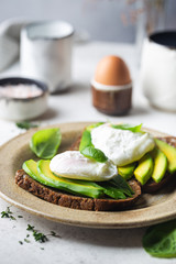 Healthy breakfast whole wheat toasted bread with avocado and poached egg over white background