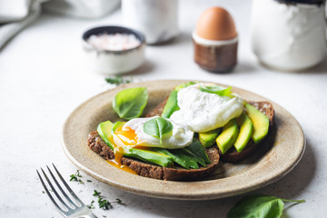 Obraz na płótnie Canvas Healthy breakfast whole wheat toasted bread with avocado and poached egg over white background
