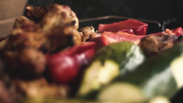 Slow-motion close-up chicken wings and grilled vegetables, (Italian squash and red pepper or red pepper / smoke from the charcoal grill).