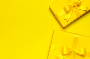 Two Bright yellow gift present box with ribbon and bow on yellow background top view copy space. Flat lay holiday background. Birthday present, March 8, Mother's Day, Valentine's Day. Congratulation