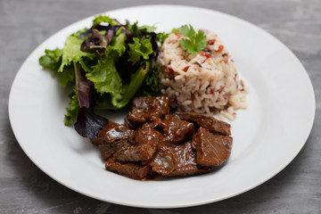 fried liver with salad and boiled rice on white plate