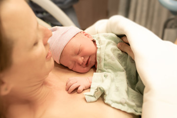 Mother holding newborn baby girl moments after birth. New life, giving birth, concept.  - obrazy, fototapety, plakaty