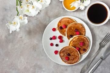 Healthy breakfast: classic american pancakes with berries, coffee and honey. Copy space, gray background. Top view.