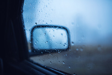 Rear view mirror with water droplets at rainy day