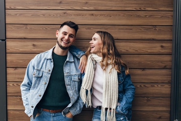 Glamorous girl in white scarf looking at boyfriend with love. Indoor portrait of handsome european man spending leisure time with cute girlfriend.