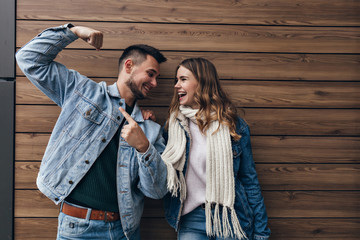 Romantic girl in knitted scarf spending time with her boyfriend. Stylish man and blonde woman looking at each other with smile.