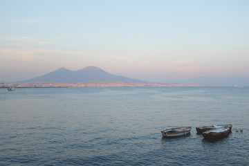 Beautiful sunset with boats and in the background volcano Vesuvius in Naples, Italy.