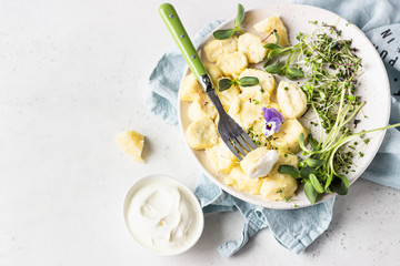 Curd and cheese dumplings served with microgreens and sour cream on a ceramic plate. Traditional...