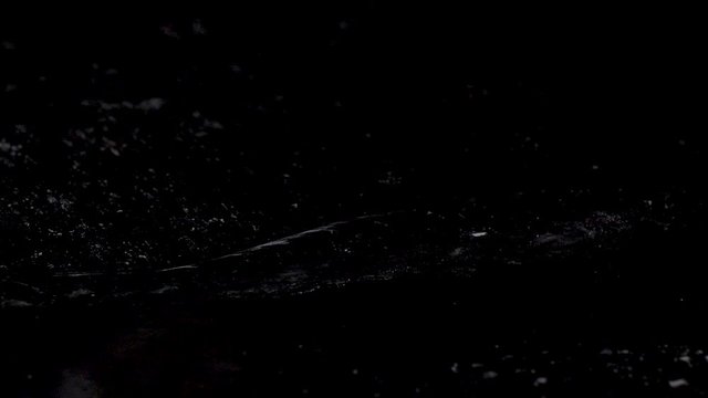 Snorting cocaine line from side, with a rolled banknote, isolated on smooth black reflective background. Close up, macro.
