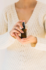 Woman holding a bottle with natural skincare product. Cosmetic and beauty concept. Blank dark bottle. Close up with a product and female hands.