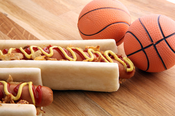 Grilled hot dogs with mustard and ketchup on the table with draft beer. Television watching basketball game with eating snacks and drinking beer