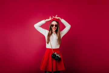 Wonderful caucasian girl in white sweater dancing with camera. Studio shot of ecstatic european...