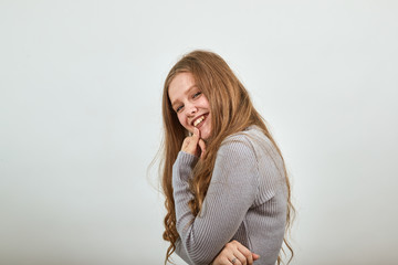 A young beautiful red haired woman in gray sweater is hunched over and smiling shyly holding chin...