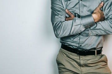 man with gray shirt, beige pants and black belt with folded arms isolated on white background