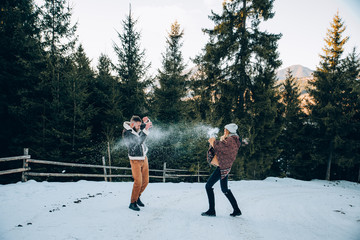 Young couple having snowball fight in forest