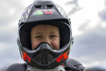 portrait of a little girl smiling in a protective helmet female child in motocross moto helmet . biker girl in motocross helmet