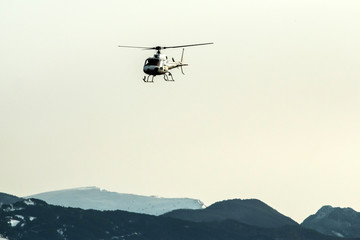 Fototapeta na wymiar An atmospheric picture shows the helicopter climbing in front of the high snowy mountains. 