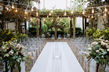 Stunning ceremonial terrace outdoors with modern transparent chairs and beautiful festoon with lots of floral compositions - obrazy, fototapety, plakaty