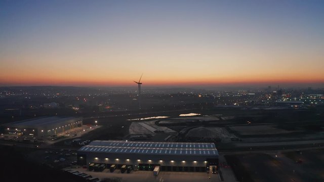 Aerial view of industrial park and skyline of Leeds city in the background. Yorkshire, UK. Forwards motion with windmill in the backdrop.