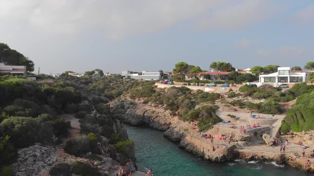 amazing drone footage of famous cala eb briut in menorca spain with tourist enjoying the sun and jumping in the turqoise waters