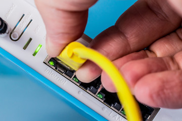 Wireless router close up. Internet connection. A person connects the ethernet cable to the...