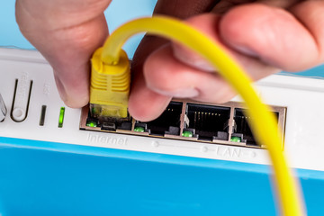 Wireless router close up. Internet connection. A person connects the ethernet cable to the...